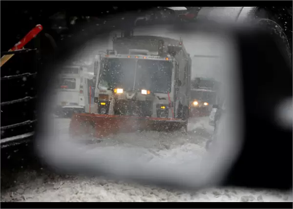 A snowplow is seen in a cars side mirror in upper Manhattan during Storm Grayson in New