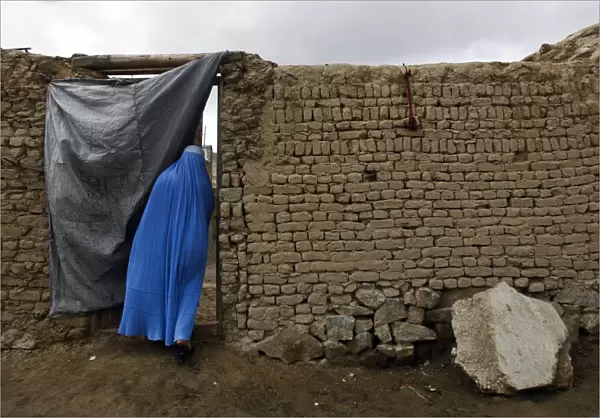 Afghan woman clad in burqa enters a house in Kabul