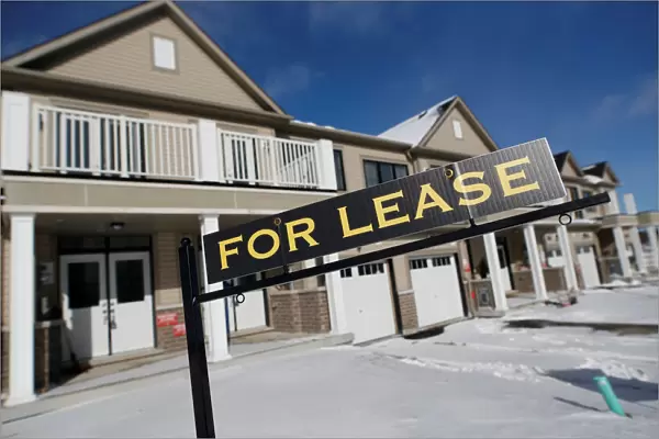 A For lease sign stands in front of a row of houses in a newly build subdivision in