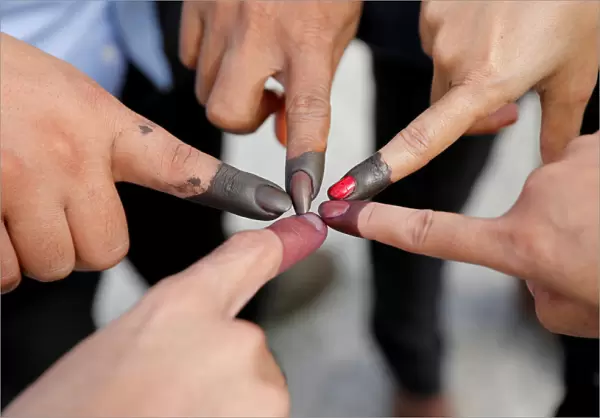 Cambodian voters take pictures of their ink stained fingers after they voted