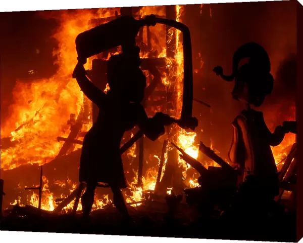 Figures of a monument burn during the last day of the Fallas festival in the early