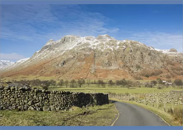 View across road, drystone walls and valley pasture towards snow covered fell, Langdale Fell, Great Langdale