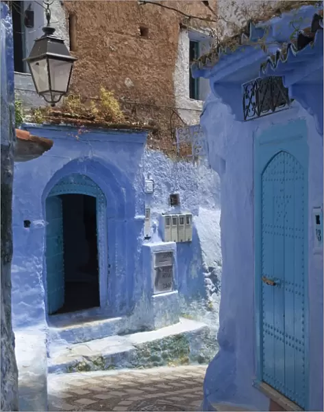 Blue door and buildings in alley of city, Chefchaouen, Morocco, april