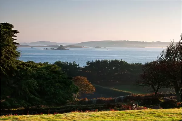 View of coastline with lifting sea mist at at sunrise, St. Martins visible in distance, Borough Farm, Tresco
