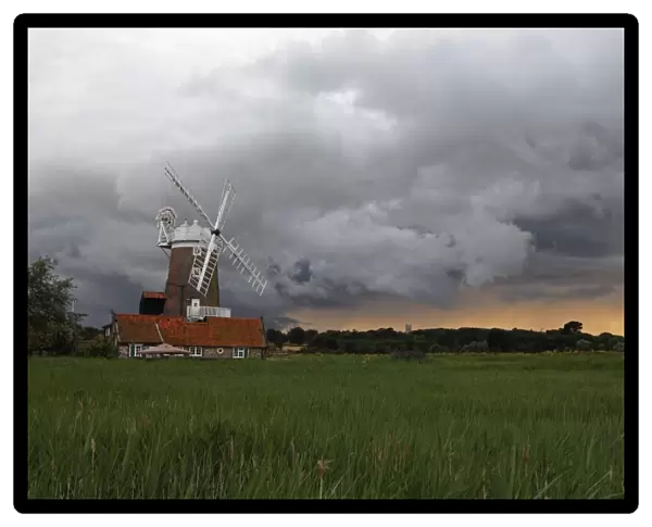 View over coastal reedbed habitat towards windmill and stormclouds, Cley Windmill, Cley Marshes, Cley-next-the-sea