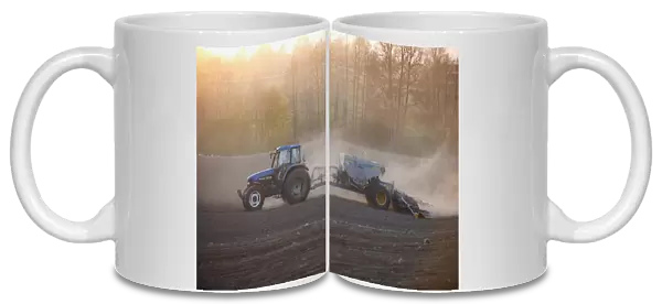 New Holland TM135 tractor with Overum seed drill, with wind blown dust in field at sunset, Uppland, Sweden, may