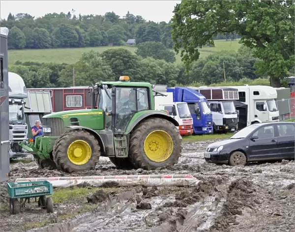 John Deere 6930 tractor pulling car out of muddy carpark at agricultural show, which was cancelled due to bad weather