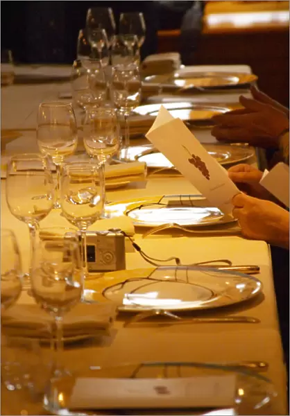 A guest holding up and reading the menu in anticipation of the meal. In the restaurant