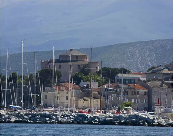 Corsica. France. Europe. Mast of boats & breakwater below citadel & other buildings of St