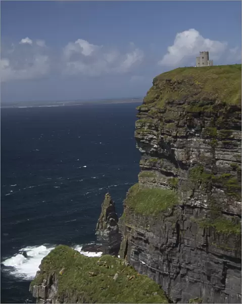 Scenic Cliffs of Moher and O Briens Tower under a blue sky and white puffy