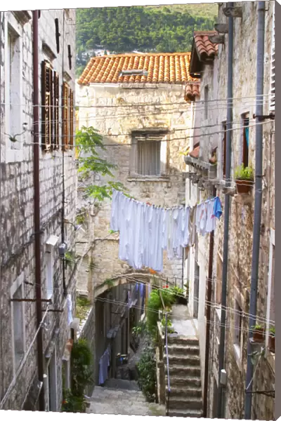 A narrow street leading down with steep steps, clothes lines hanging across the street