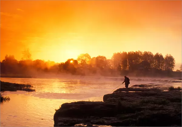Fisherman at sunrise on Venta River waterfall at city of Kuldiga in Kurzeme region