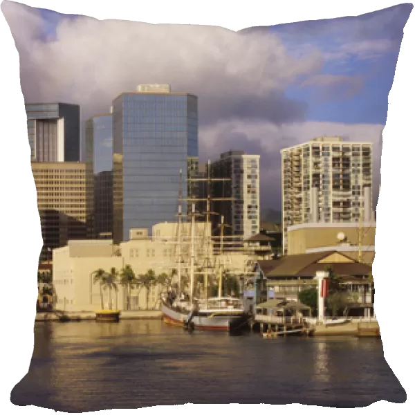 Modern skyscrapers contrast with vintage sailing ships of a bygone era in Honolulu harbor