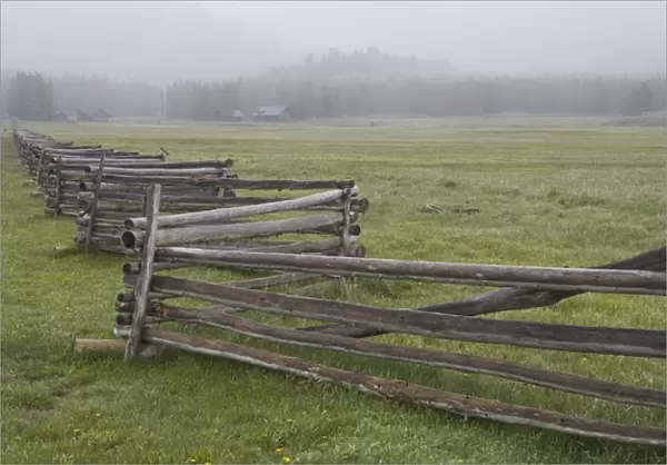 USA, Idaho, Sawtooth Mountains. Split-rail fence divides field in misty farm country