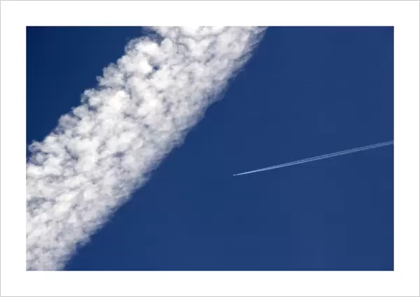 Vapor contrails from high flying jet aircraft. The larger has been blown apart by