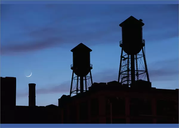 USA, New Jersey, Jersey City, Rooftop water towers and setting crescent moon