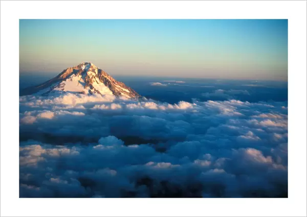 Aerial view of snow covered Mt. Hood poking through the clouds just at an Oregon sunset