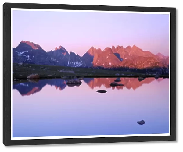 BRIDGER WILDERNESS, WYOMING. USA. Peaks of the Continental Divide reflected in tarn at sunset