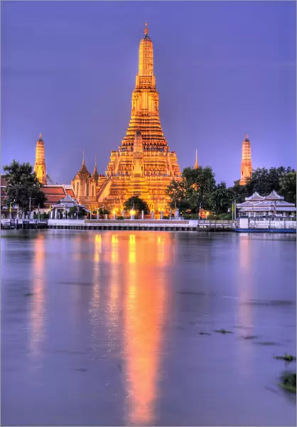 Thailand, Bangkok, Wat Arun. Ornate Buddhist temple reflects in river at dusk. Credit as