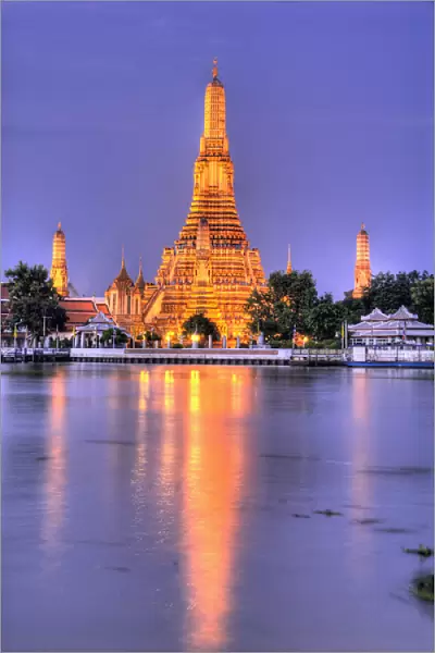 Thailand, Bangkok, Wat Arun. Ornate Buddhist temple reflects in river at dusk. Credit as