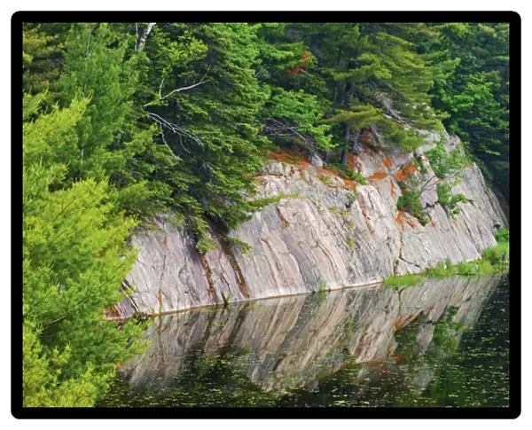 Canada, Ontario, Killarney District. Granite reflected in water
