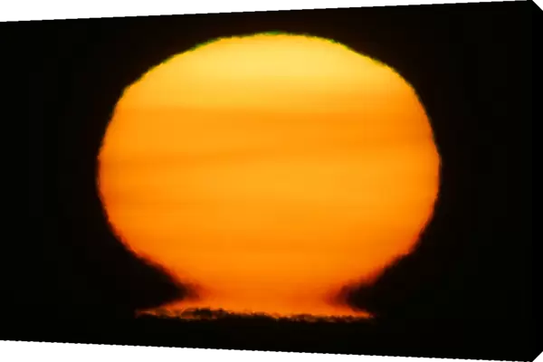 USA, Alaska, Homer. Sun at sunset distorts to look like a nuclear fireball. Credit as