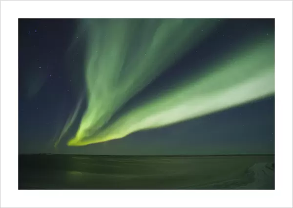 Shimmering curtains of green Aurora borealis dance in the southern sky over a lagoon