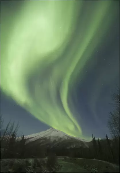 Curtains of green aurora borealis dance in the sky over unnamed peaks in the Central