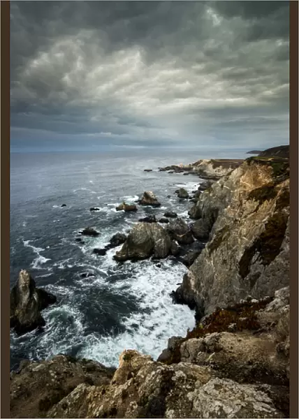 North America, USA, California. Clouds approaching the cliffs and surging waves at Bodega Head