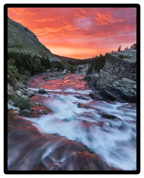 Brlliant sunrise sky over Swiftcurrent Falls in Glacier National Park, Montana, USA