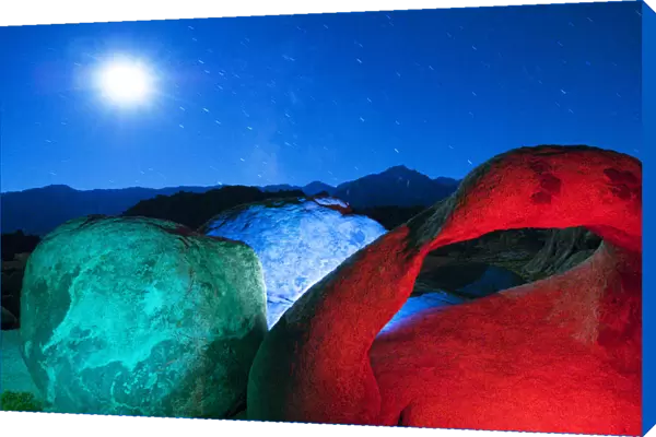 USA, California, Alabama Hills. Mobius Arch and rocks lit with colors on moonlit night