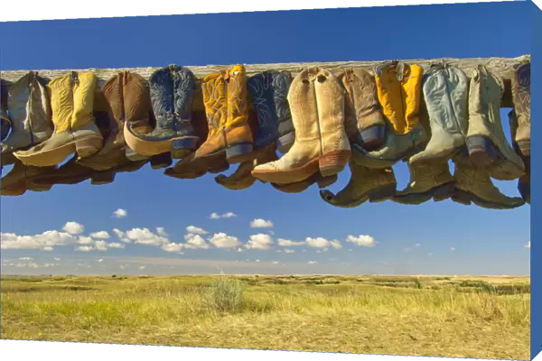 Canada, Saskatchewan, Great Sand Hills. Old cowboy boots on posts on prairie. Credit as
