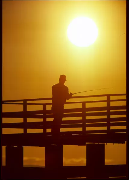 Silhouette of man fishing from a pier
