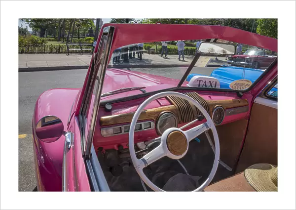 View into drivers seat of classic convertible pink American car parked in Vieja