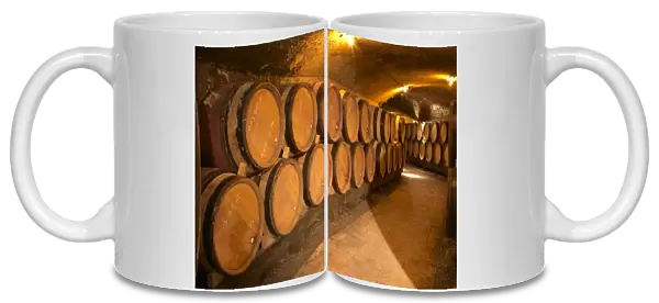 Wooden barrels with aging wine in an underground corridor in the cellar of Guigal in Ampuis