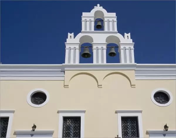 Greece, Santorini. Yellow church wall and white bell tower against dark blue sky