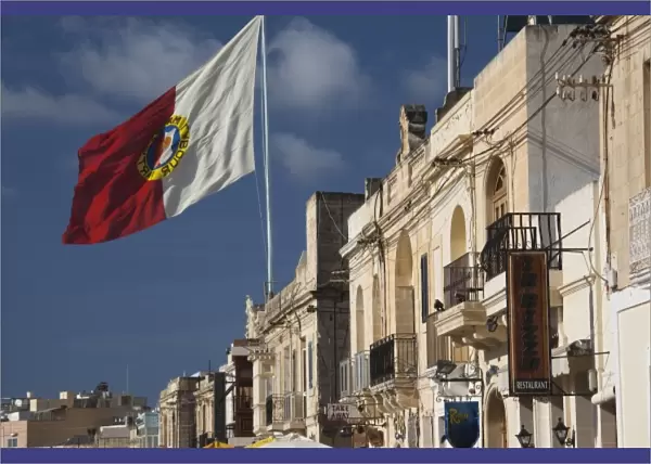 Malta, Southeast, Marsaxlokk, waterfront buildings and flag