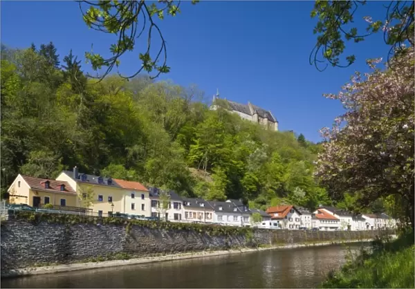 Luxembourg, Vianden. Town buildings and Vianden castle along Our River, morning