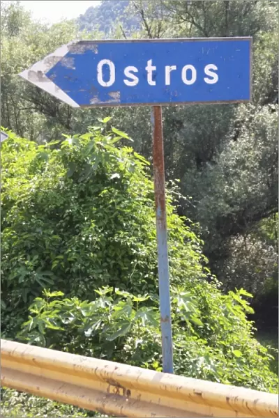 Blue rusty Road side sign pointing left saying Ostros. Near Dupilo, Golubovic Montenegro