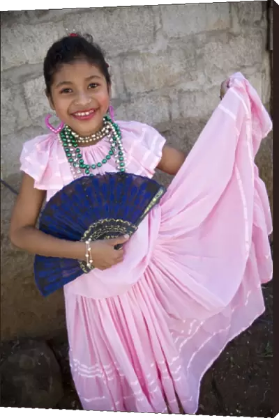 Nicaragua, Granada. Girl with fan in traditional dress after dance in Villa Esperanza barrio