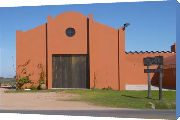 A view over the main winery building and a sign to the winery. Painted in ochre red