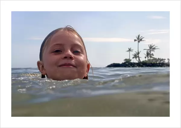 USA, Hawaii, Oahu. A young girl enjoys swimming in the waters of the Kahala Hotel & Resort