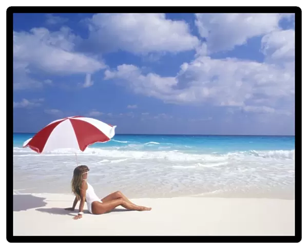 Woman sitting on tropical beach with umbrella (MR)
