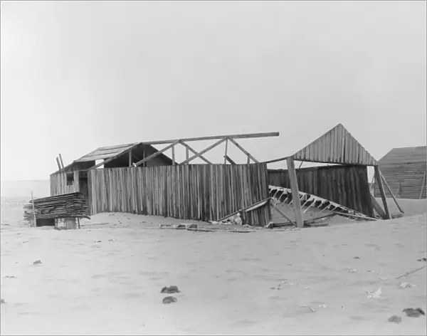 The camp at Kitty Hawk, North Carolina showing its damaged condition at the time of Wilburs arrival on April 10, 1908. The old 1902 building is on the left, its side walls still standing but its roof and north end gone. The remains of the 1902 glider are on the ground. Photograph by the Wright Brothers, 1908