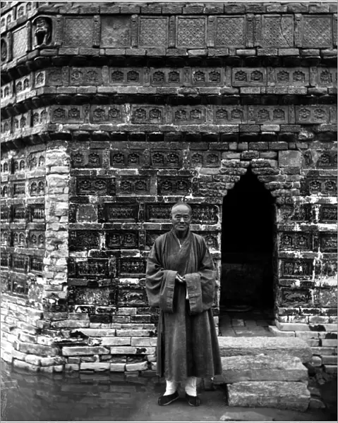 A Buddhist monk standing outside the entrance of the Iron Pagoda, built in the mid-11th century, at the Youguo monastery in Kaifeng, China. Photographed c1912