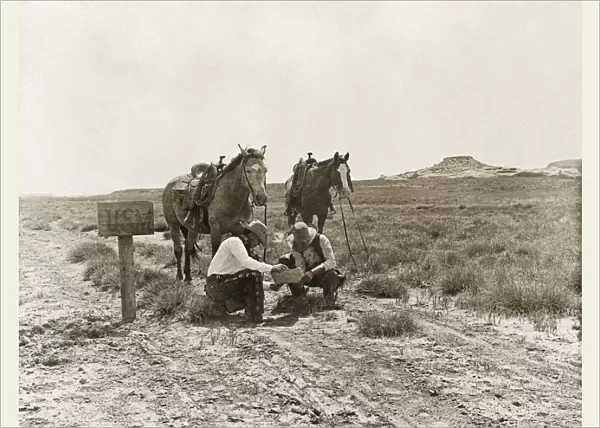 TEXAS: COWBOYS, c1907. Two cowboys reading mail next to a USM postbox near the