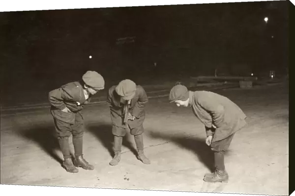 BOYS SHOOTING CRAPS, 1912. Three boys gambling with dice at midnight in the street in Providence