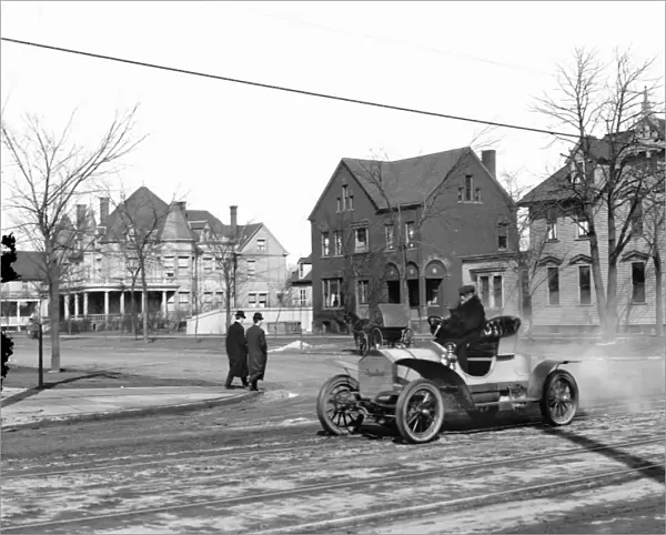 AUTOMOBILE, c1905. Man driving an automobile through an American town. Photograph