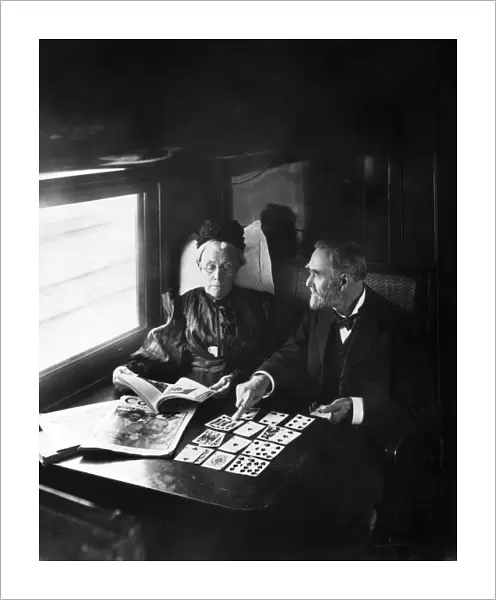 TRAIN PASSENGERS, 1905. A couple reading magazines and playing solitaire in a California