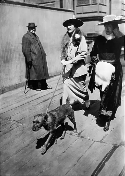 EASTER PARADE, 1915. Two women walk a dog down 5th Avenue during an Easter parade, New York